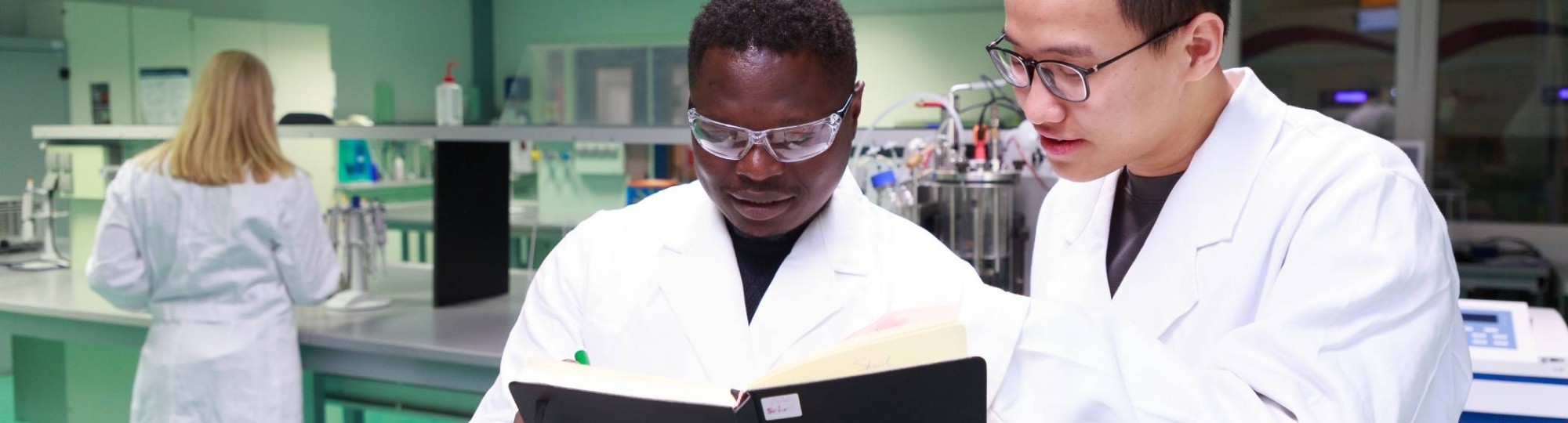 Studenten master Life Sciences Alain Barhasima en Dat Le werken in een biologielab. Op de rug Lisan Scholten