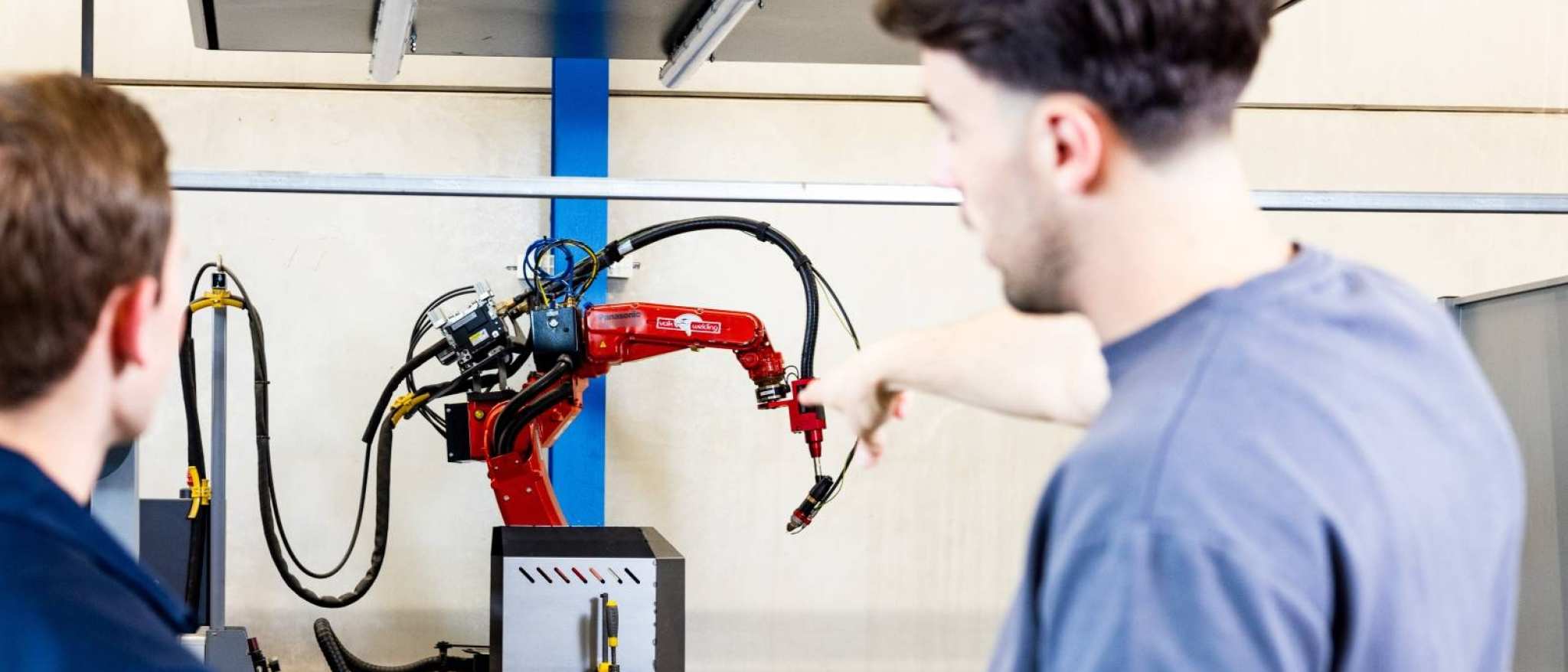 Technische Bedrijfskunde studenten Jort en Derk samen bij robot arm.