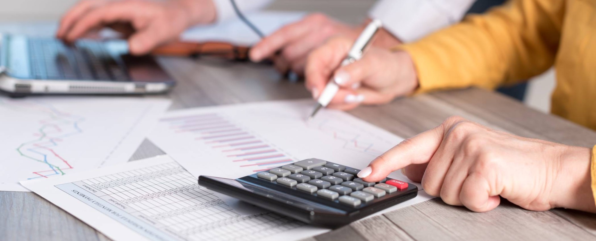 Foto van rekenmachine, vier handen en een laptop voor projectpagina Associate lectoraat Sustainable Finance & Tax