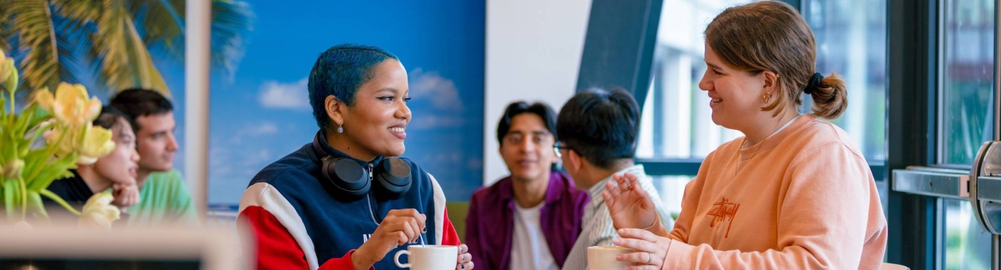 Students Noa, Chadionne, Tam, Diego, Nyugen and Andrei relaxing and drinking coffee in the Hangar on the Arnhem campus of HAN University of Applied Sciences.