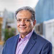 Portretfoto Sadegh-Seddighi, lector Waterstof. Donkerblauw colbert en lila overhemd, locatie hal 6