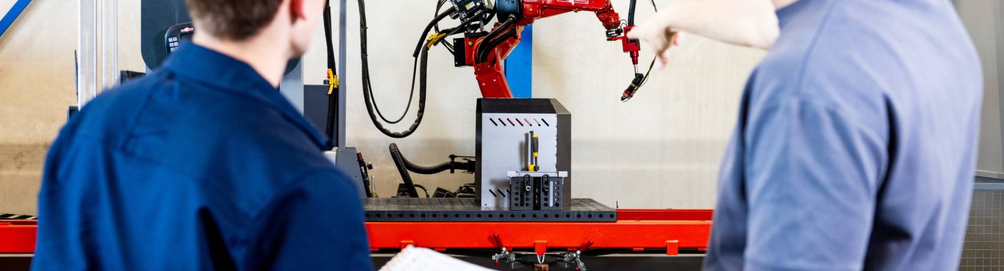 Technische Bedrijfskunde studenten Jort en Derk samen bij robot arm.