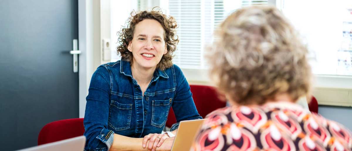 2 docenten zitten aan tafel in overleg