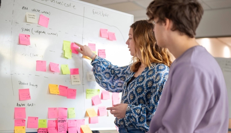 Studenten plakken post-its, projectonderwijs in de klas.
