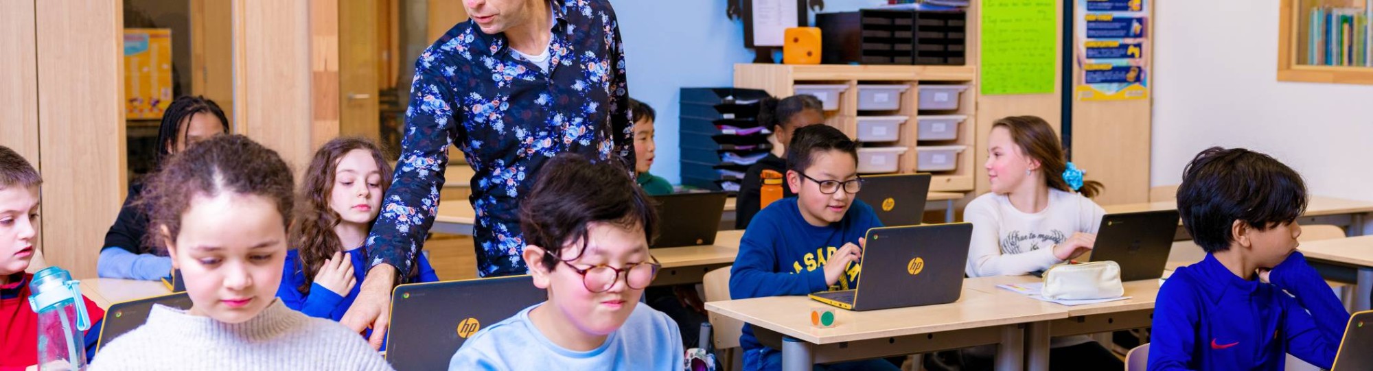 Groep 5,6,7 op de school Da Vince. De leerlingen zitten in de klas achter de laptop terwijl de leraar rond loopt. 