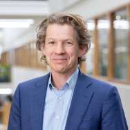 Jos Sanders, werkzaam bij lectoraat Leren tijdens de loopbaan. lichte blauwe blouse, kobalt blauw jasje