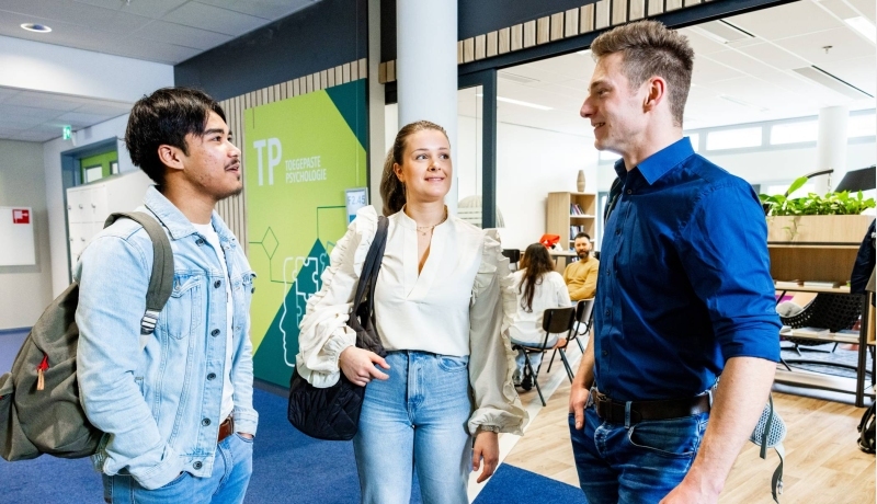 drie studenten van de opleiding toegepaste psychologie kletsen met elkaar op de HAN