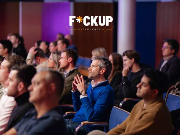 Een groep mensen luistert aandachtig tijdens een FuckUp Night 