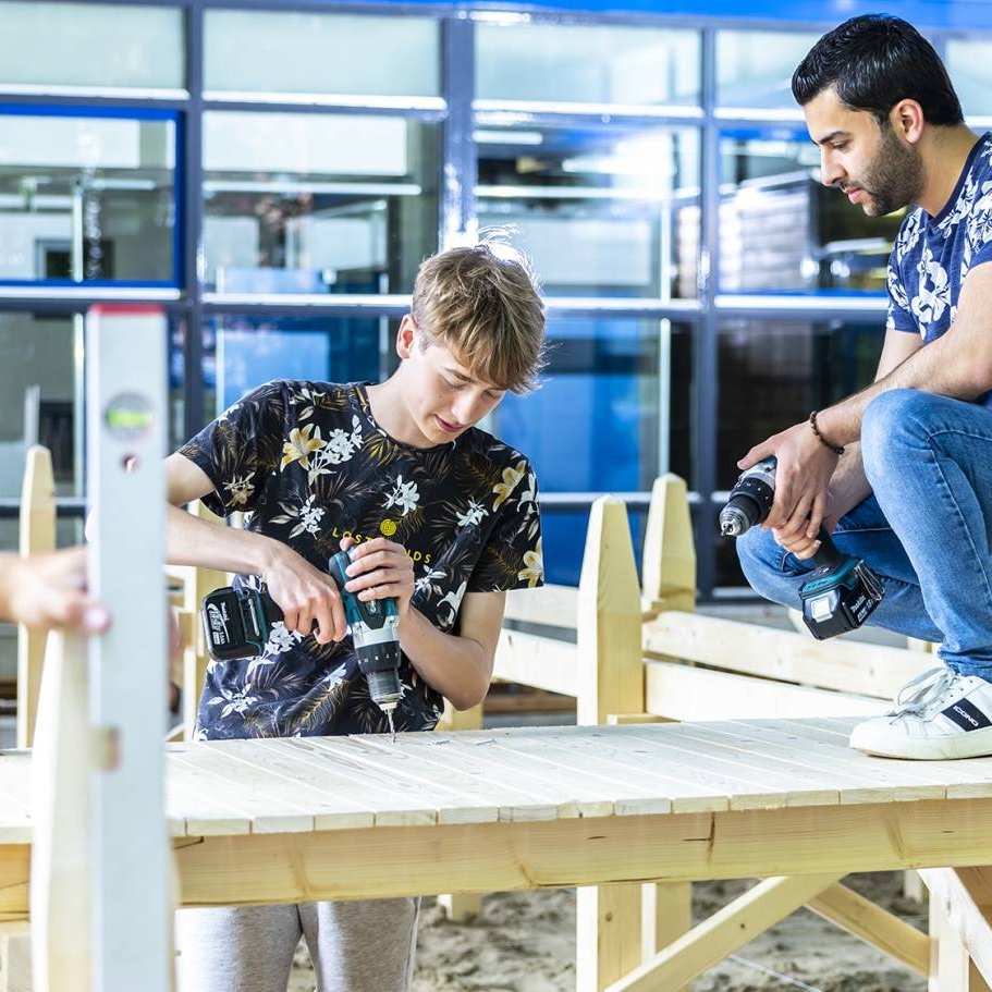 4 studenten civiele werken aan de houten steiger onder het gebouw van de opleiding