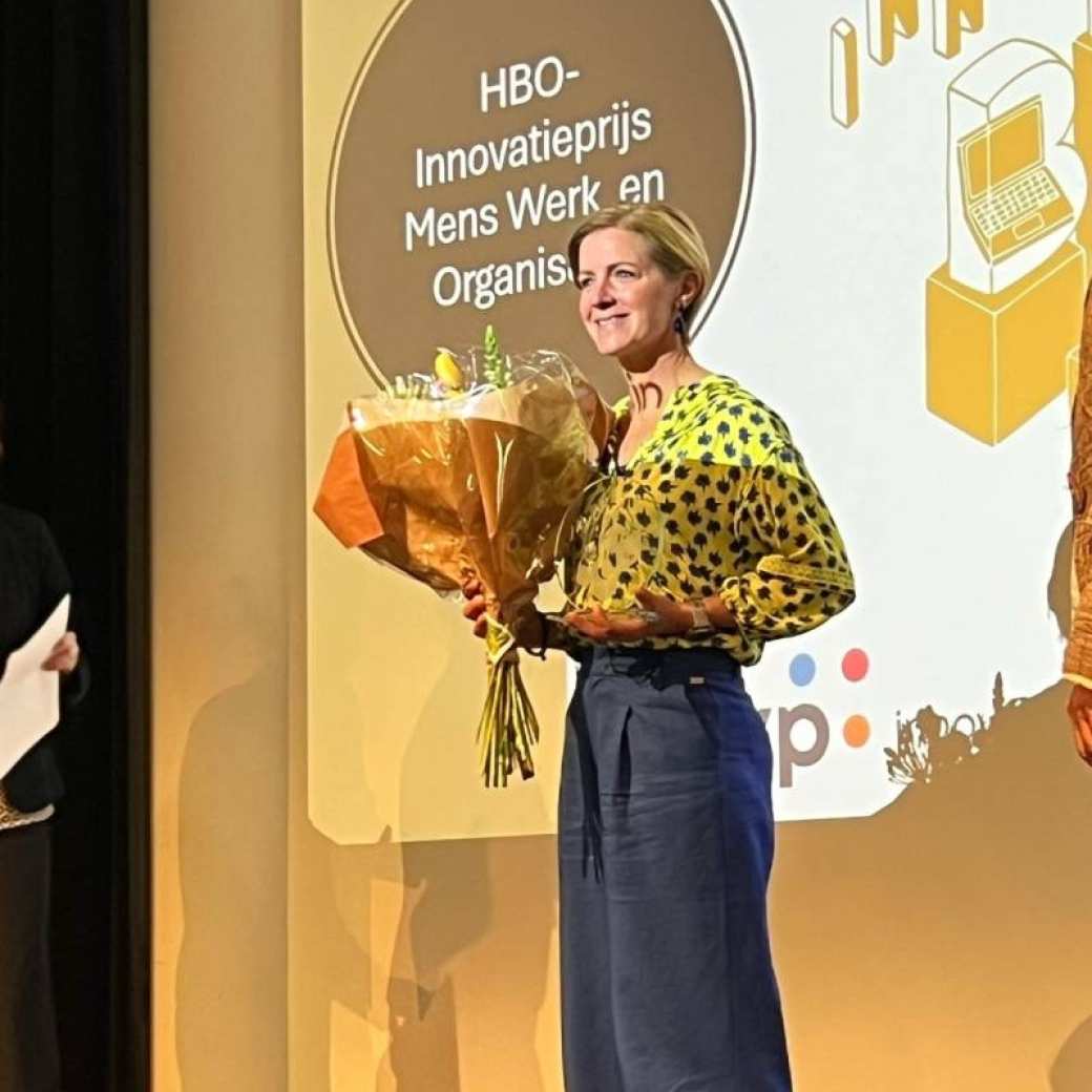 Foto van Maartje van Spijker, alumnus Learning & Development in Organisations en winnaar van de HBO-innovatieprijs. Ze heeft een bos bloemen in haar hand.