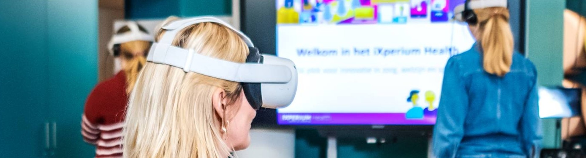 Foto van iXperium Health, waar 2 studenten en een docent een VR-bril op hebben.