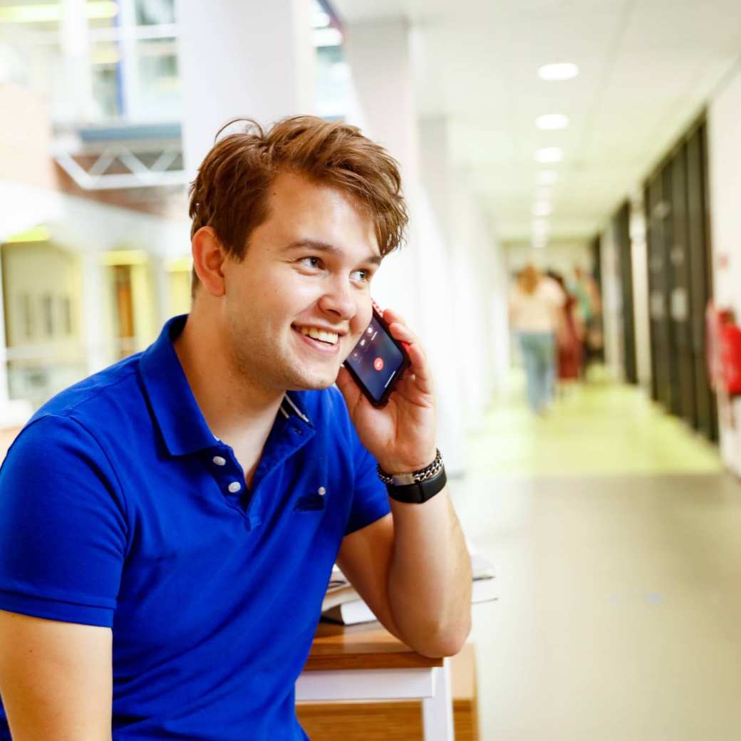 man bellen telefonisch overleg student hal gang