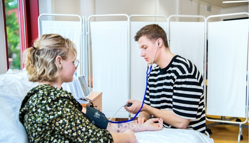 2 studenten oefenen met bloeddruk meten tijdens les Verpleegkunde deeltijd