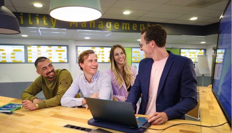 Docent geeft meerdere studenten uitleg via een laptop