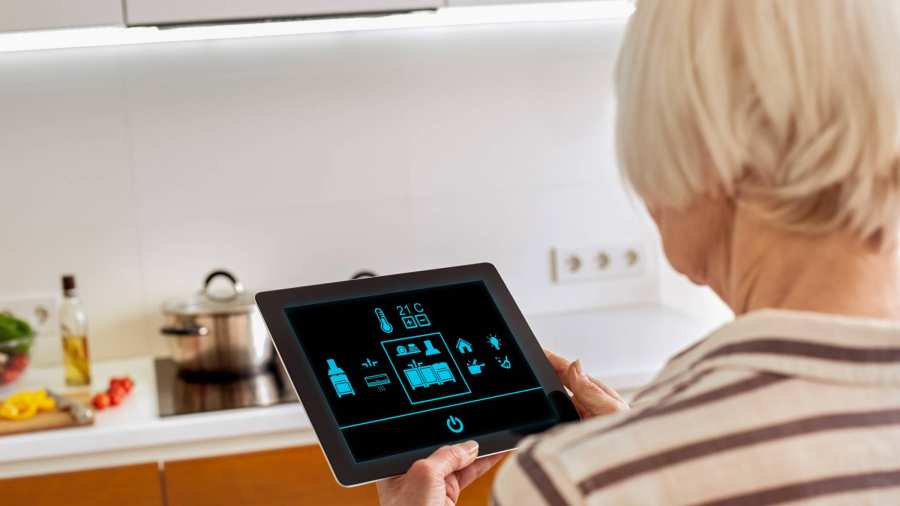 Oudere dame werkt met een tablet om op een innovatieve manier haar woning te bedienen.