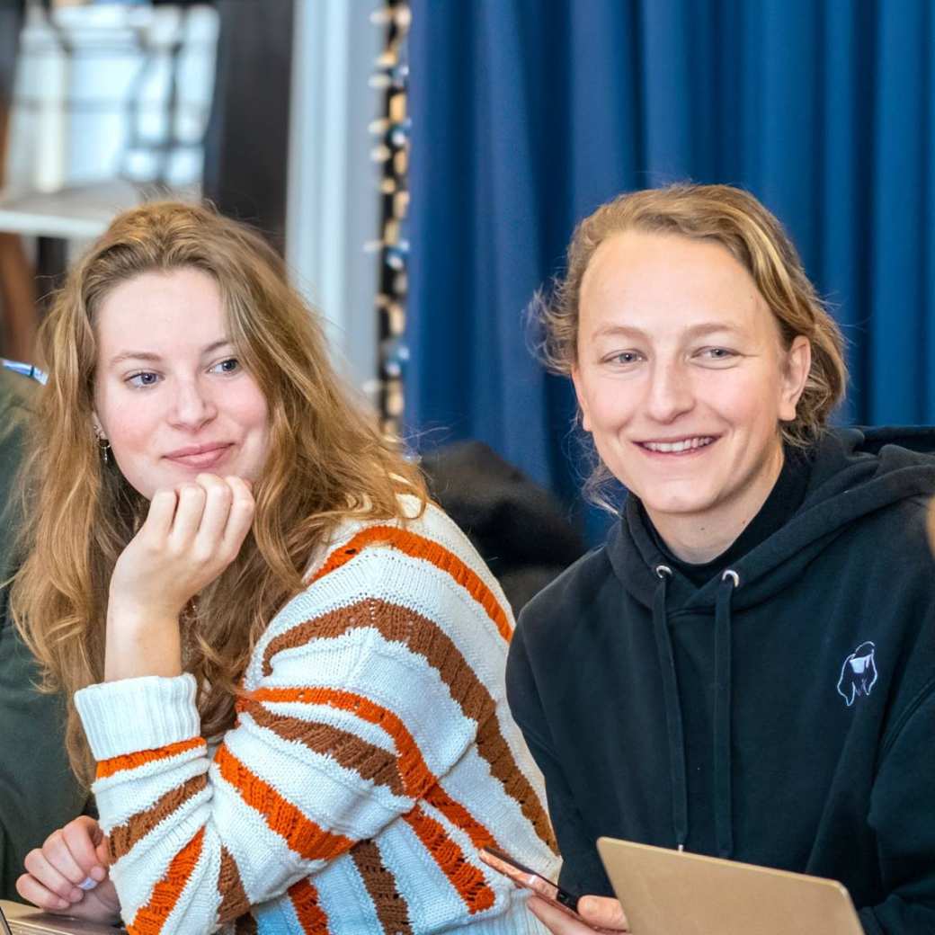 Studenten zitten samen, lachen met elkaar.