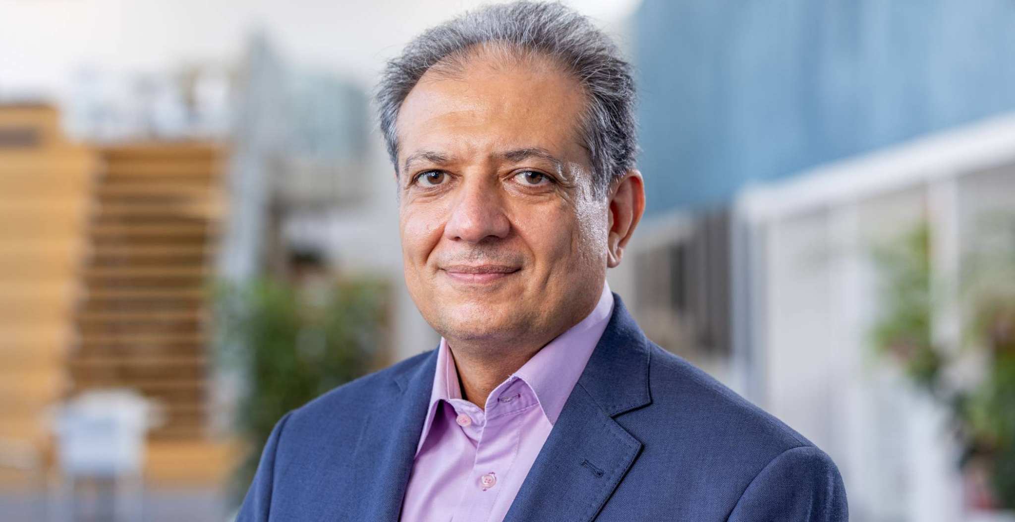 Portretfoto Sadegh-Seddighi, lector Waterstof. Donkerblauw colbert en lila overhemd, locatie hal 6