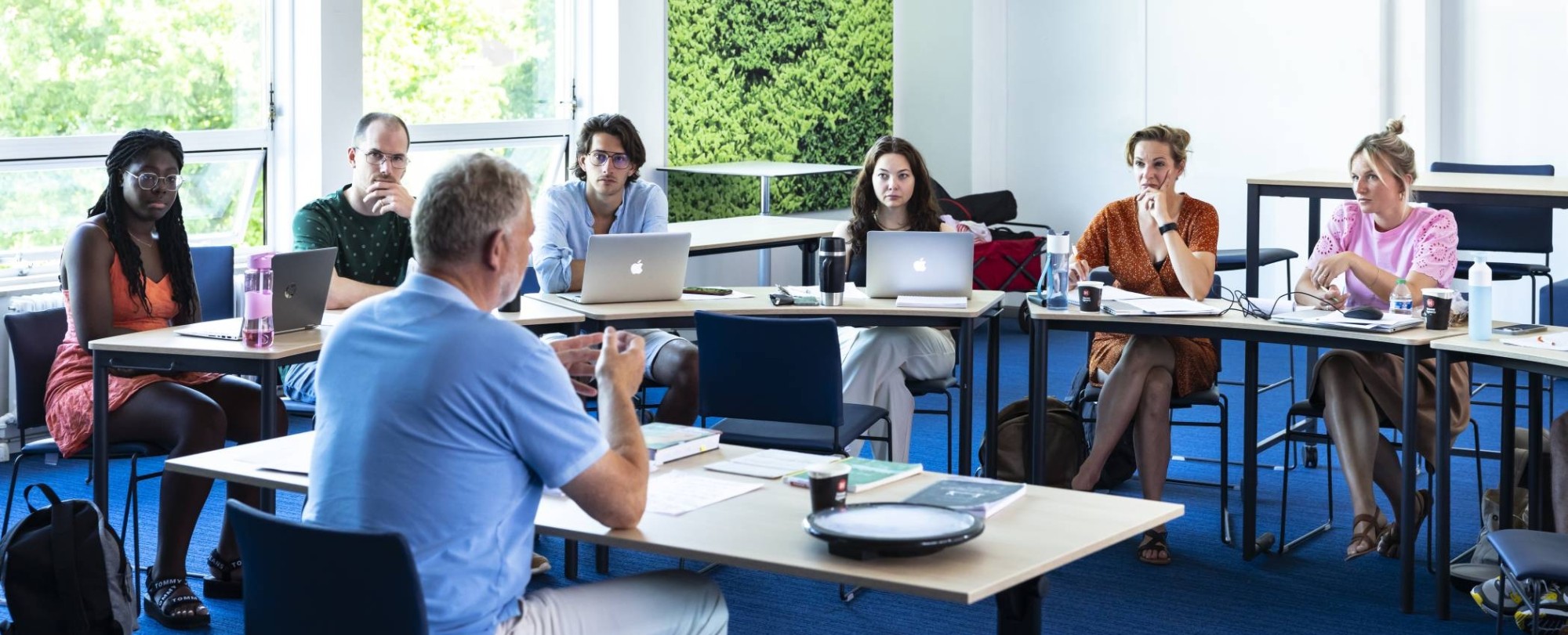 Studenten van de Master Social Work luisteren aandachtig terwijl de docent uitleg geeft.