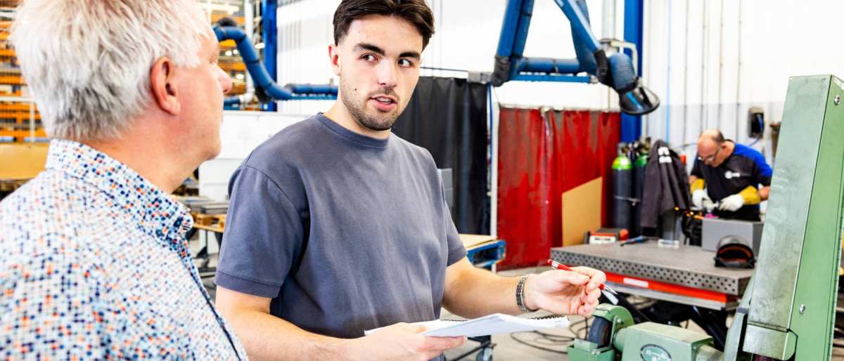 Technische Bedrijfskunde student overlegt met stagebegeleider bij machine.