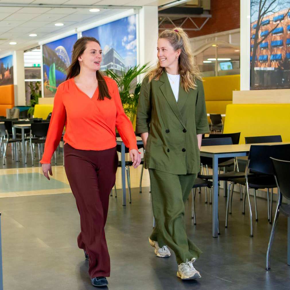 Docenten van de opleiding Bedrijfskunde deeltijd in gesprek op de HAN-campus in Arnhem, Ruitenberglaan 31. Ze lopen door de kantine en lachen.