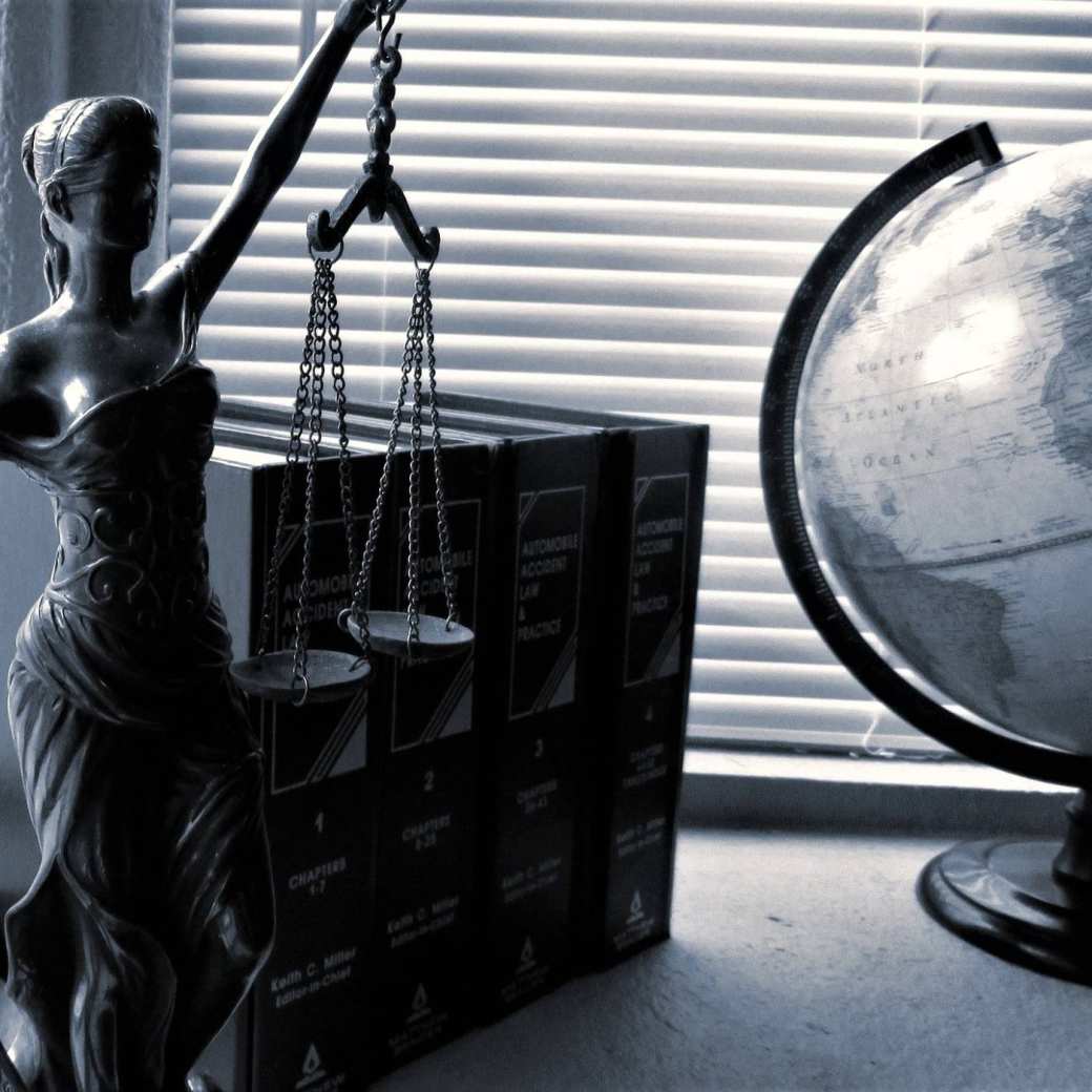 Vrouwe justitia met wettenbundels en wereldbol