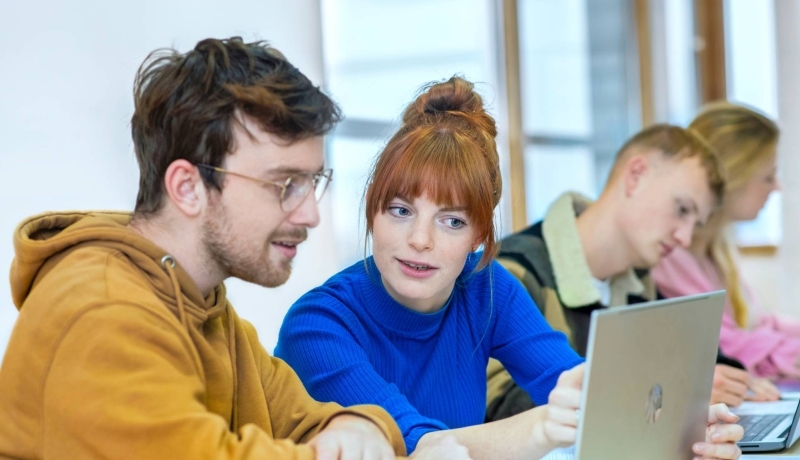 Twee studenten kijken samen naar de laptop