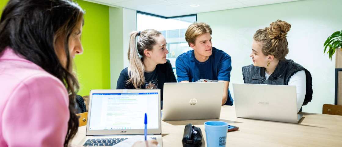 Studenten Human Resource Management (HRM) overleggen in de studio met de laptop erbij