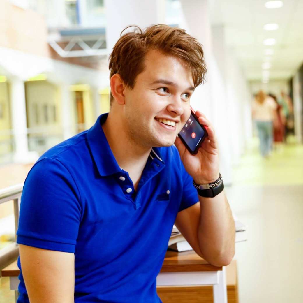 man bellen telefonisch overleg student hal gang