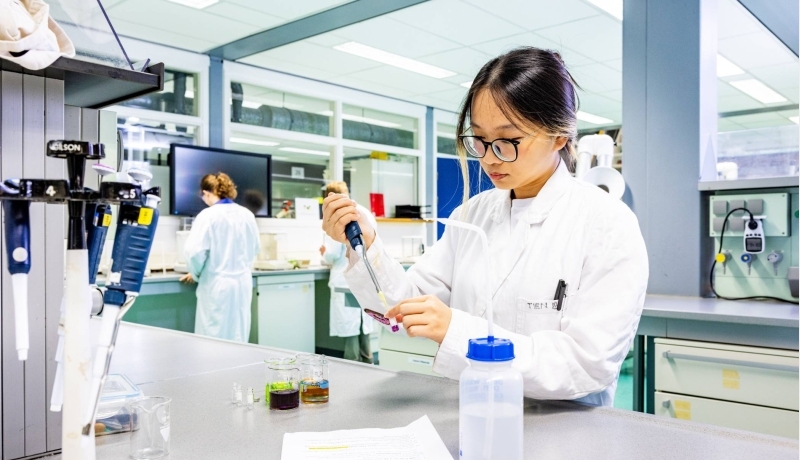 student aan de slag met een pipet in het chemielab
