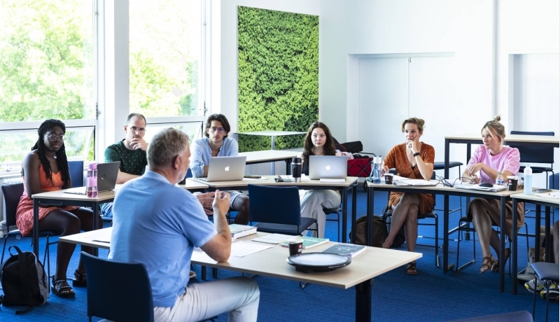 Studenten van de Master Social Work luisteren aandachtig terwijl de docent uitleg geeft.