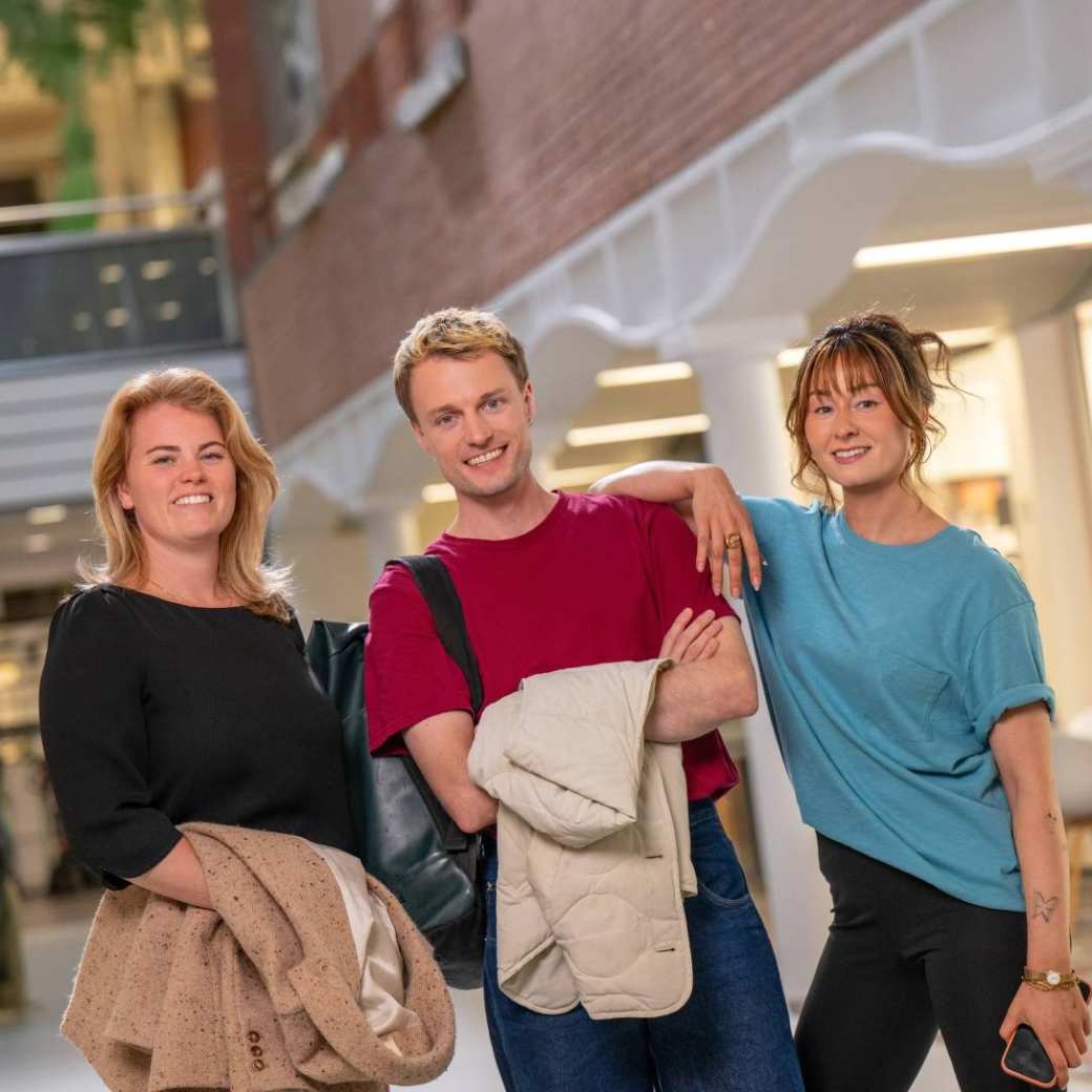Groep studenten staat in hal met jassen uit en lachen