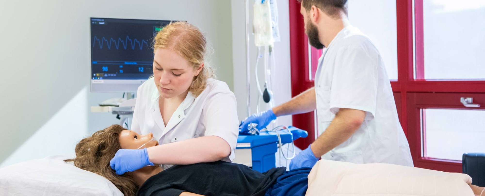 2 studenten zijn pop aan het onderzoeken tijdens les Verpleegkunde voltijd