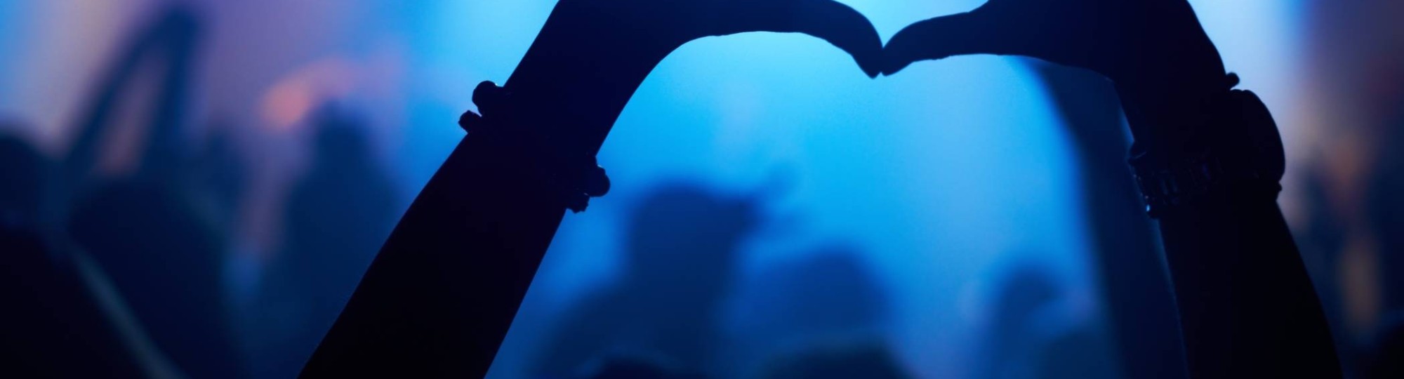 Bezoeker voor het podium van een festival maakt met haar handen een hartje.