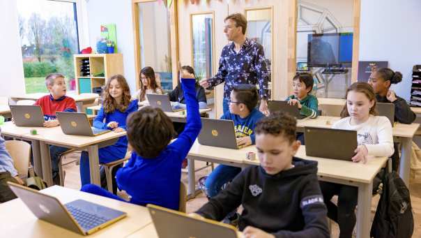 Jongen steekt vinger op in klas en docent kijkt naar hem
