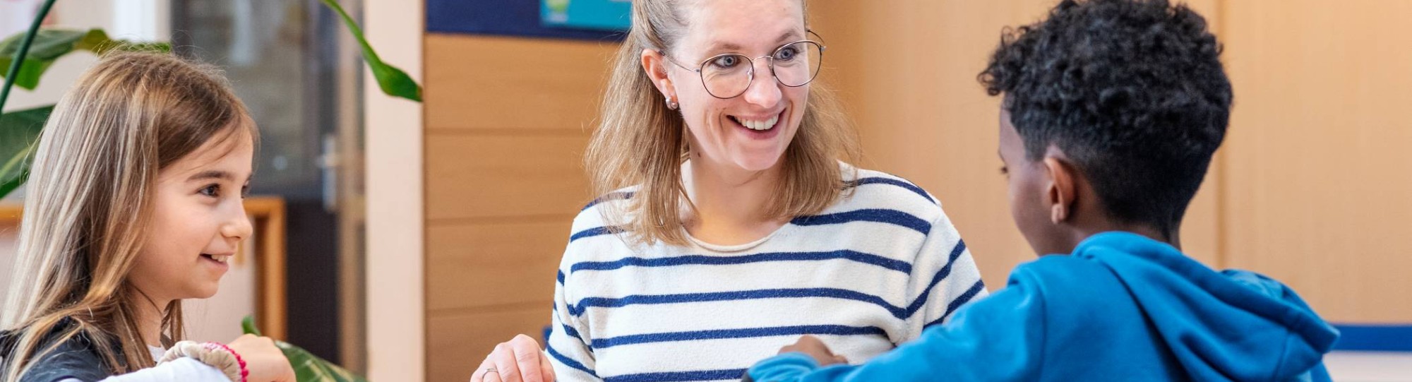 Associate Degree Pedagogisch Educatief Professional met twee leerlingen aan tafel met stiften