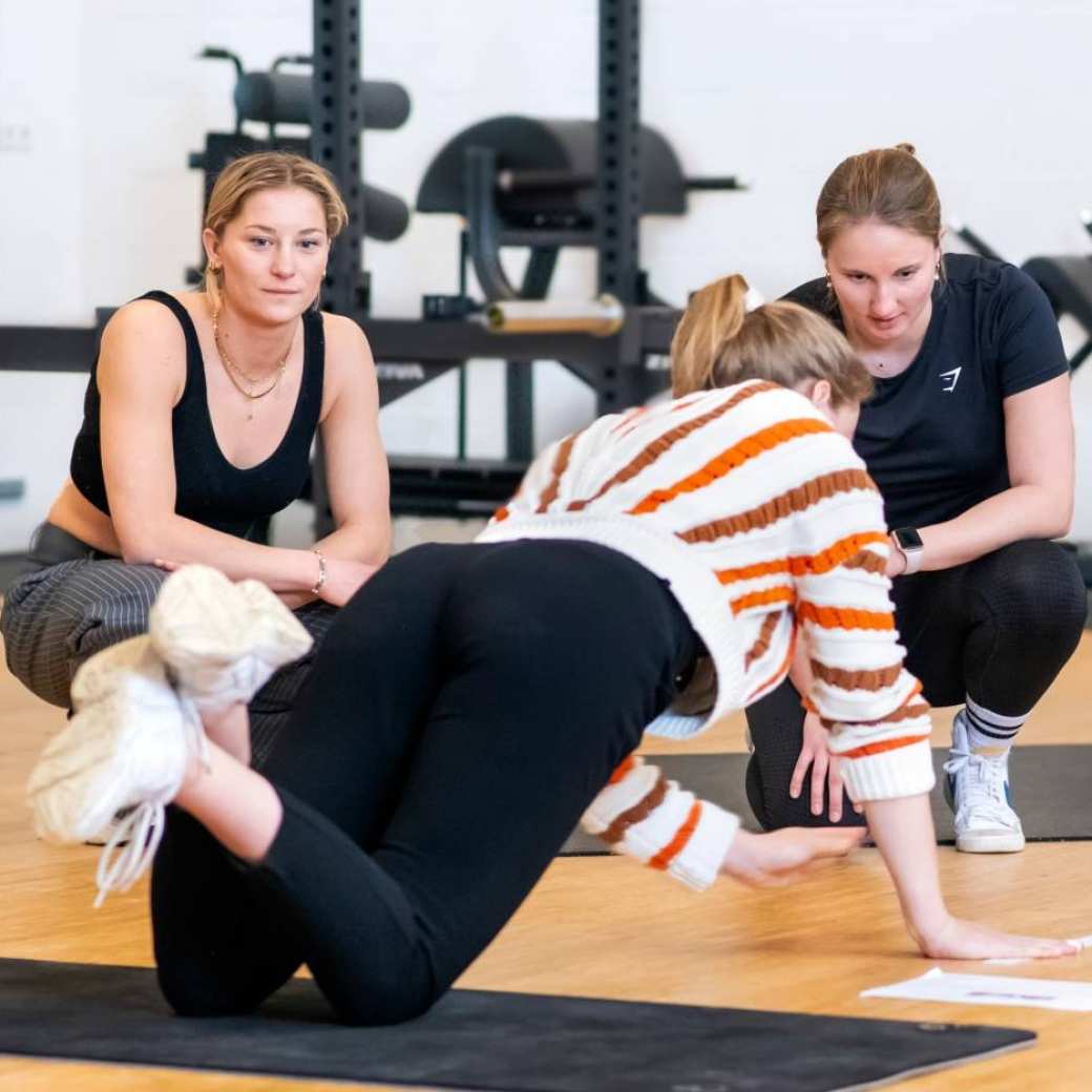 Studenten voeren op de vloer van een sportzaal een opdracht uit.