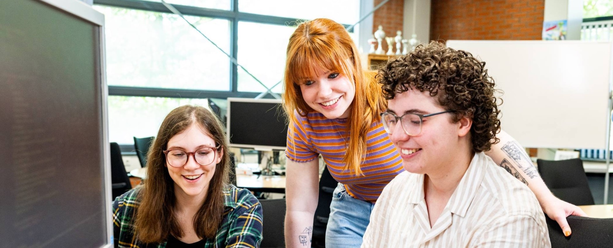 Drie cursisten Programmeren in Python aan het werk achter een computer.