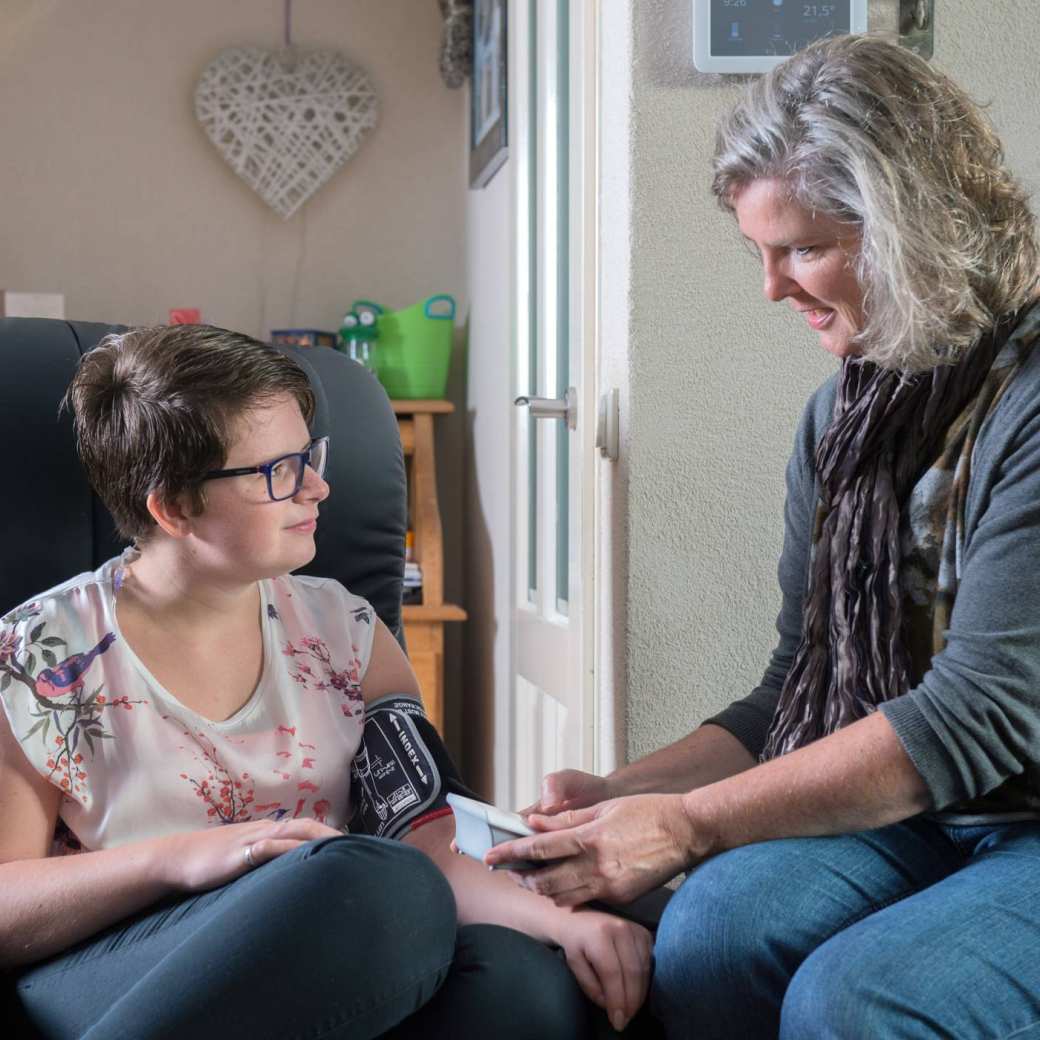verpleegkundige van de thuiszorg controleert de bloeddruk bij een jonge chronisch zieke patiente