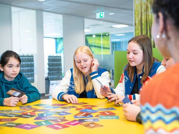 Kinderen in gesprek over het kaarspel dat voor ze op tafel ligt
