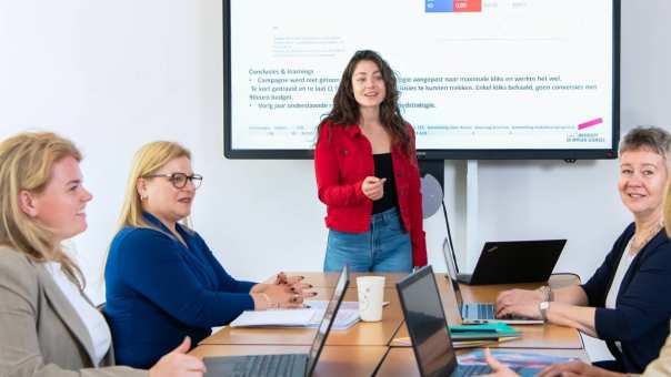 Deelnemers en docenten van de post-hbo Bedrijfskunde in overleg, lachend. 