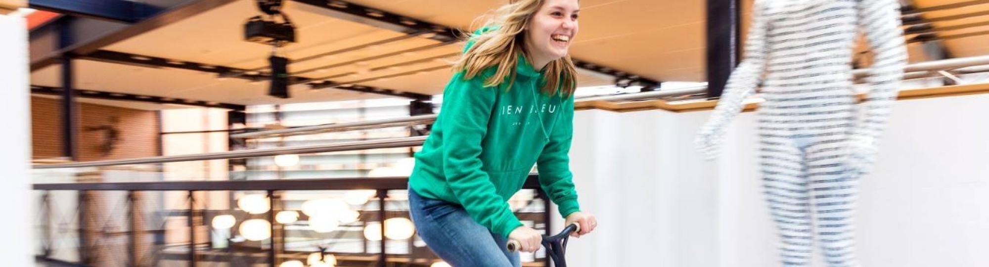 Foto van student Meike Geurtsen die op een step door de gang sjeest.
