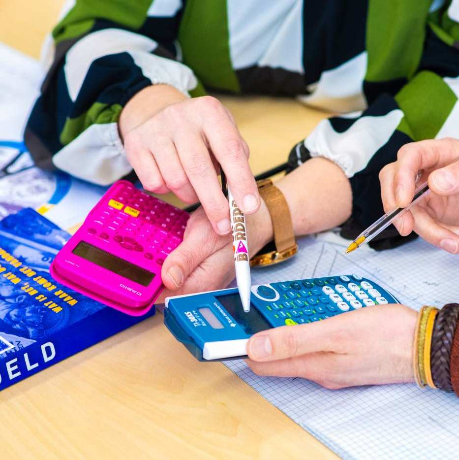 Een student wijst met een pen op een blauw rekenmachine.