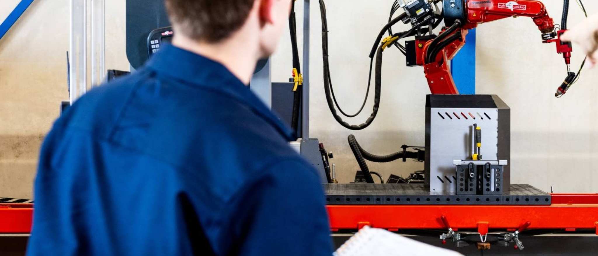 Technische Bedrijfskunde studenten Jort en Derk samen bij robot arm.