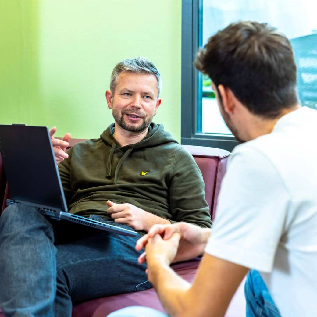 Werkgever vraagt SLIM Scholingssubsidie aan op laptop, in gesprek met werknemer.