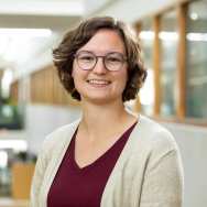 Portretfoto Manon van Zanten, bordeaux t-shirt, beige vest erover