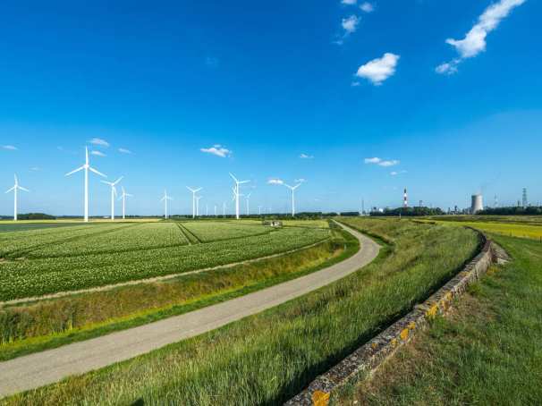 5682eed0-d48e-11ee-897d-875903b75f9e Nederlands landschap met blauwe lucht, windmolens en energiecentrale