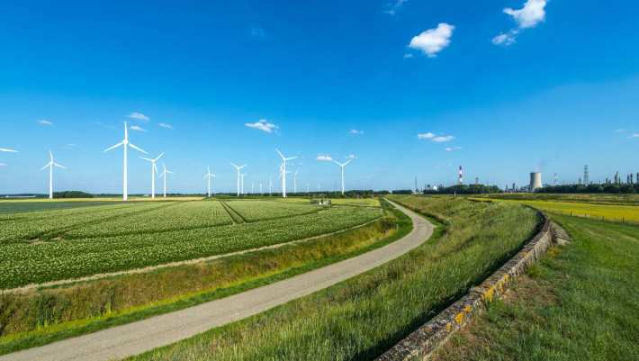 Nederlands landschap met blauwe lucht, windmolens en energiecentrale