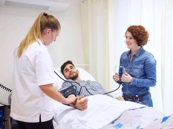 Voltijd student Verpleegkunde en docent aan het bed van patiÃ«nt meten bloeddruk-1