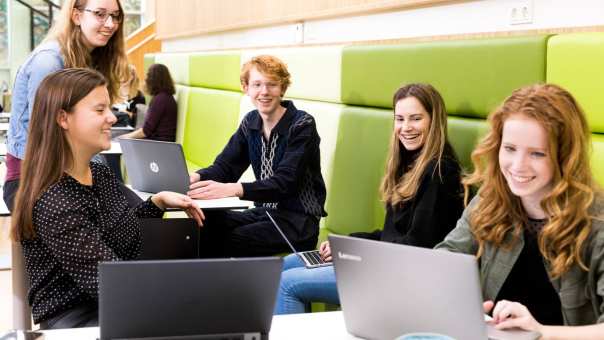 Vijf ALPO studenten kijken lachend naar een laptop scherm