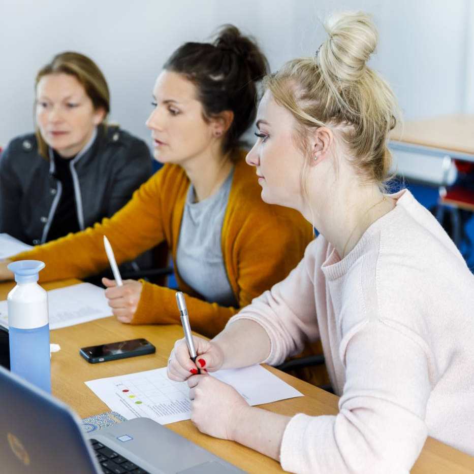 drie studenten kijken naar een laptop